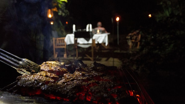A grill with meat being cooked outdoors at night. - Explorer by eco team -Dambana (Mahiyanganaya)
