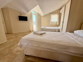 Un dormitorio con dos camas, una televisión de pantalla plana y una ventana con cortinas.