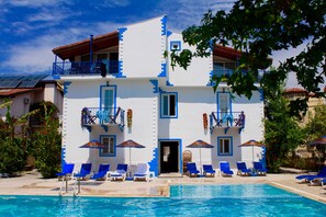 Un edificio de dos pisos con piscina, ventanas de marco azul y balcones.