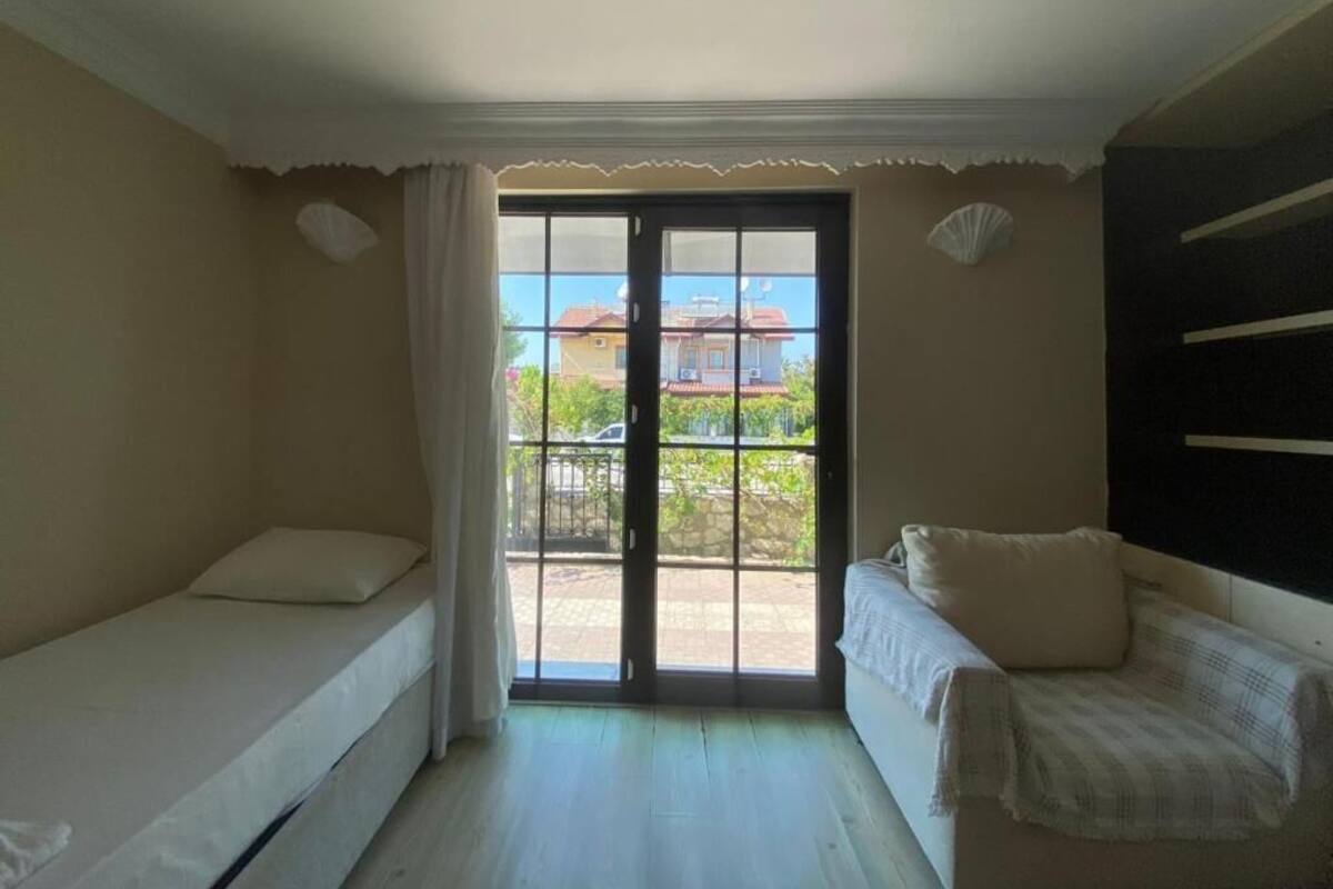 Una habitación con cama, sofá y puerta corrediza de vidrio que da a un área exterior.