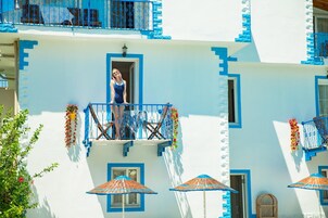Un edificio con balcones, una persona en uno de ellos y una puerta.