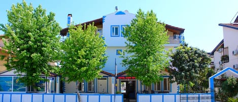 A hotel with a blue and white facade, a visible entrance, and a signboard.