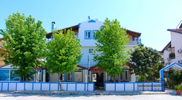 Un hotel con fachada azul y blanca, entrada visible y un letrero.