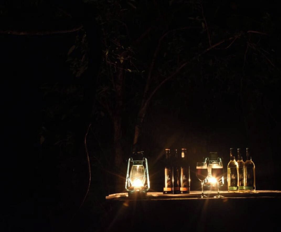 Una mesa con botellas y vasos, posiblemente para servicio de bebidas, ubicada al aire libre por la noche.