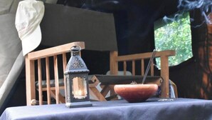 A tent interior with a table set for a meal, a lantern, and a smoking pipe. - Explorer by Eco Team - Wasgamuwa National Park (Maraka)