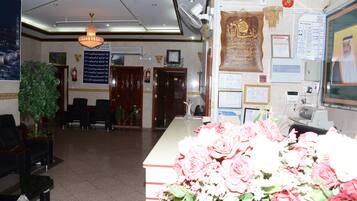 A reception area with a desk, chairs, a chandelier, a plant, and various informational posters.