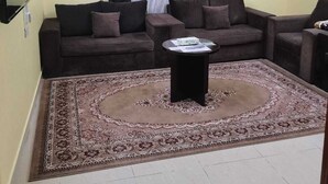 A living room with a sofa set, a coffee table, and a patterned rug. - AL EAIRY SERVICED APARTMENTS 3 (Madinah)