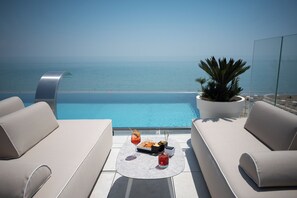 A rooftop terrace with a pool, two sofas, a table with drinks, and a potted plant. - Unico Hotel Caorle (Caorle)