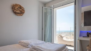 A hotel room with a bed, a desk, and a view of the beach.