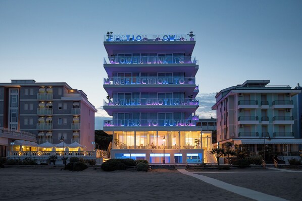 A multi-story hotel with balconies and a neon sign that reads "EMOTION FLOWER."