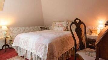 A bedroom with a bed, a chair, a nightstand, and a lamp.
