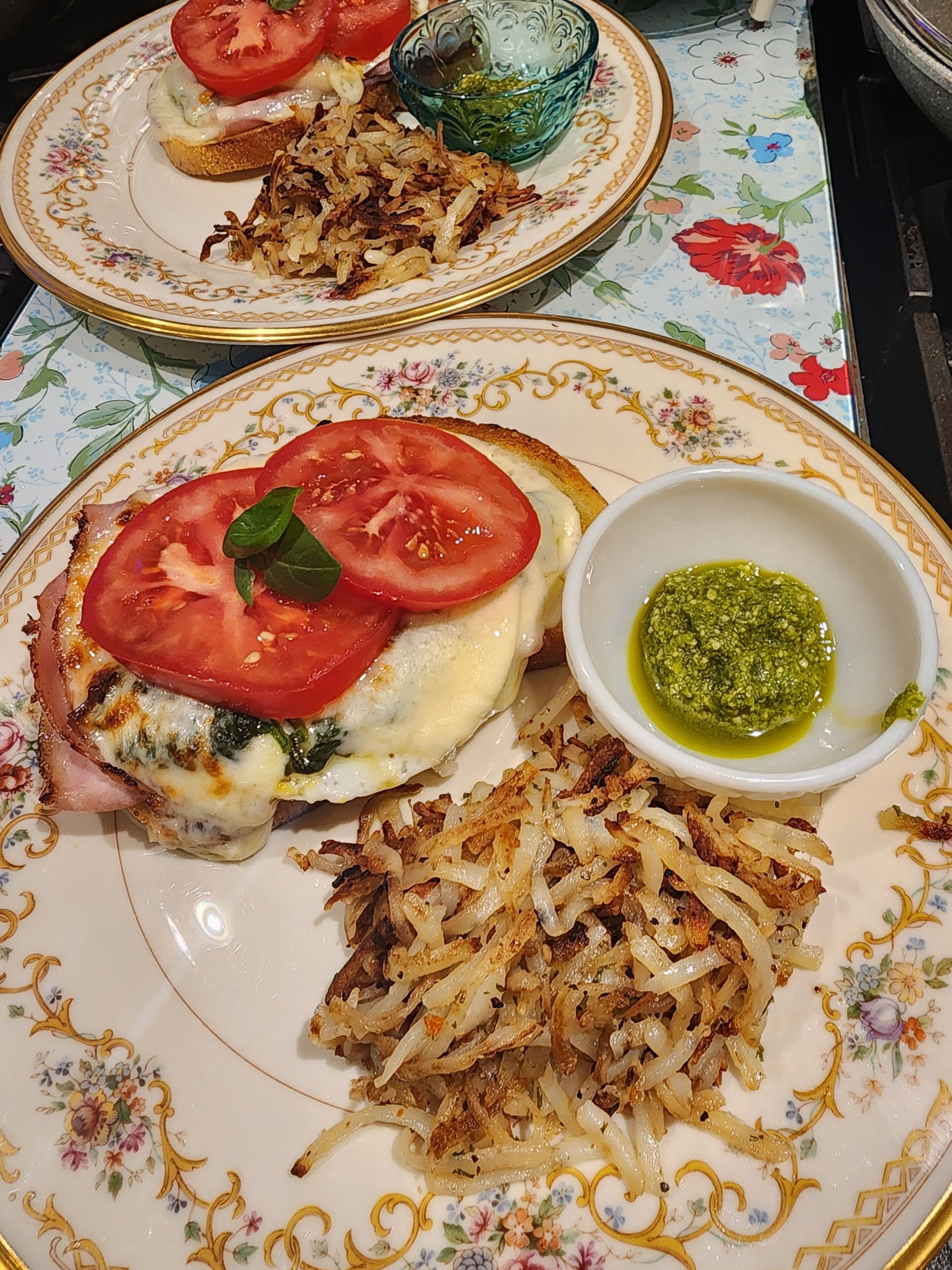 A plate with a sandwich, a side of potato pancakes, and a bowl of green sauce.