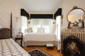Une chambre à coucher avec un grand lit, une table de chevet, une commode, un miroir et une cheminée.