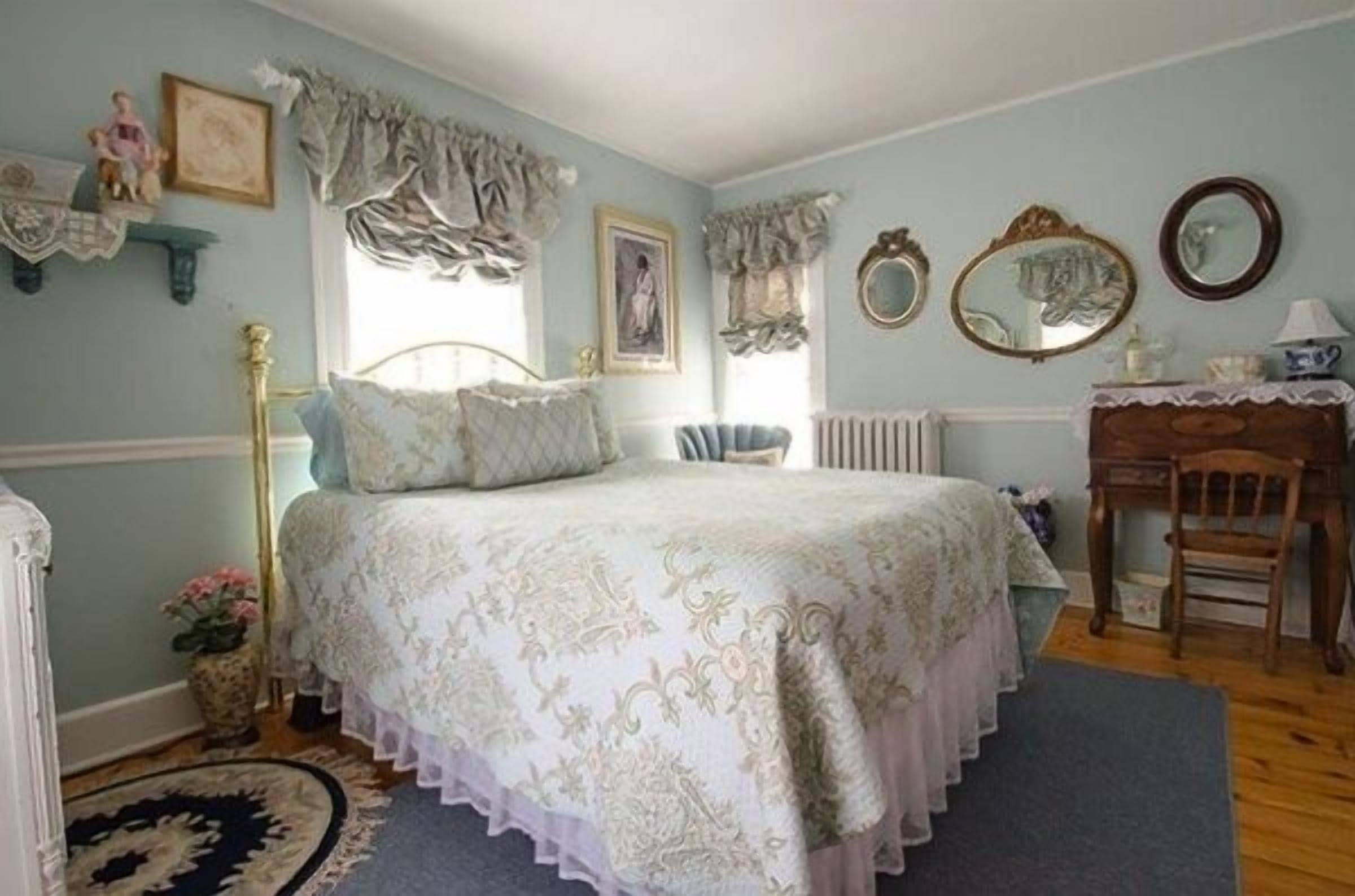 Een slaapkamer met een bed, een stoel, een dressoir en een spiegel.