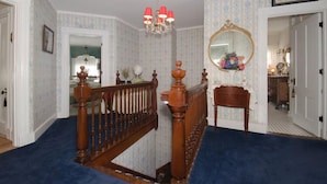 A staircase with a wooden railing, a chandelier, and a mirror on the wall. - The Tea Rose Inn at Plymouth (Plymouth)
