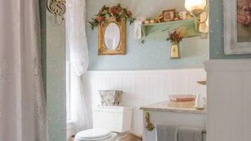 A bathroom with a toilet, a sink, a mirror, a chandelier, and a decorative wall.
