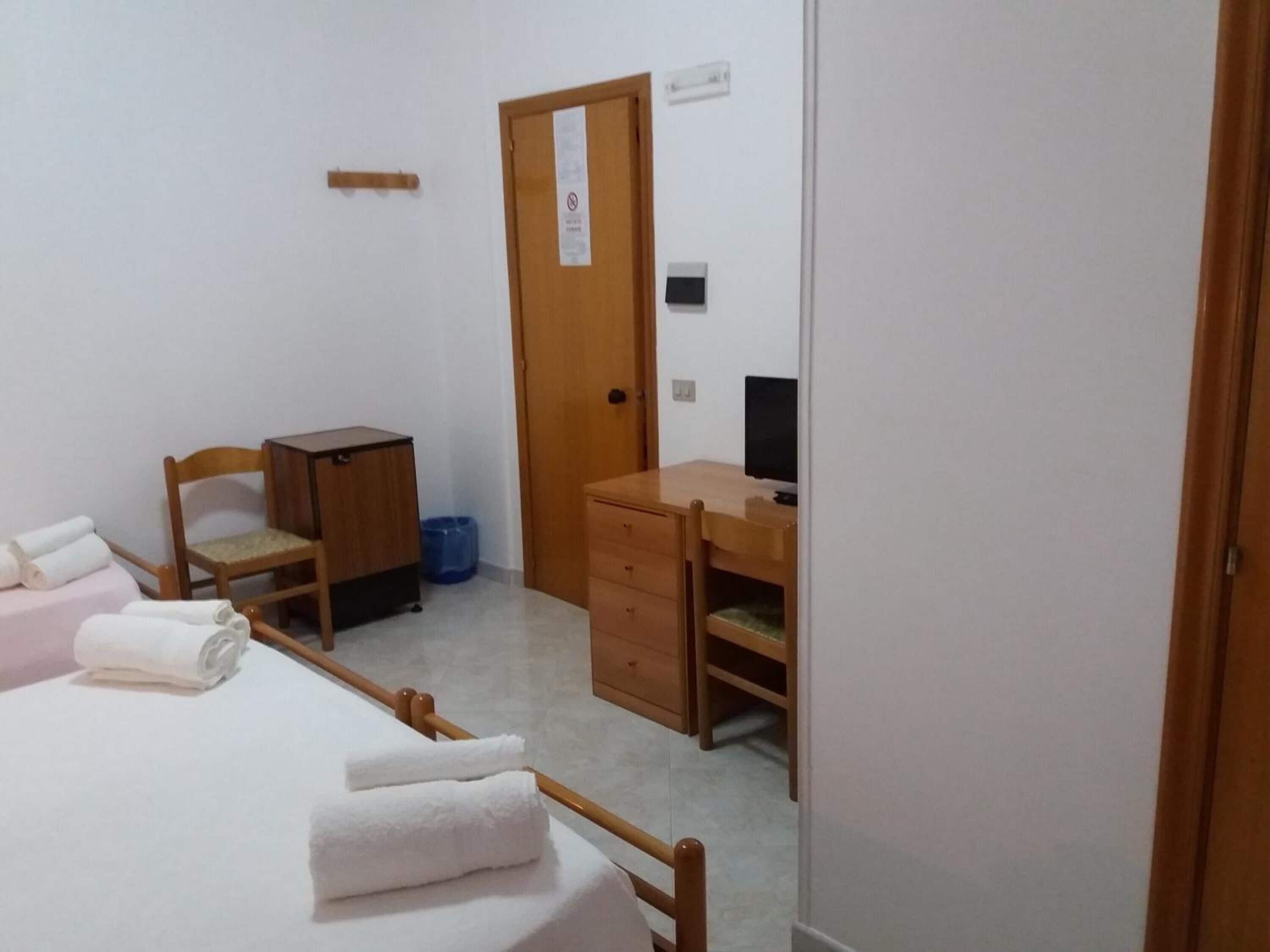 A small, clean room with a bed, a desk, a chair, and a wardrobe.