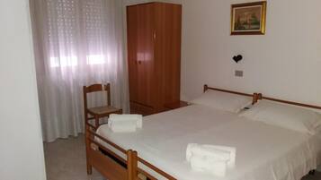 Une chambre à coucher avec un lit en bois, une chaise, une armoire et un tableau accroché au mur.