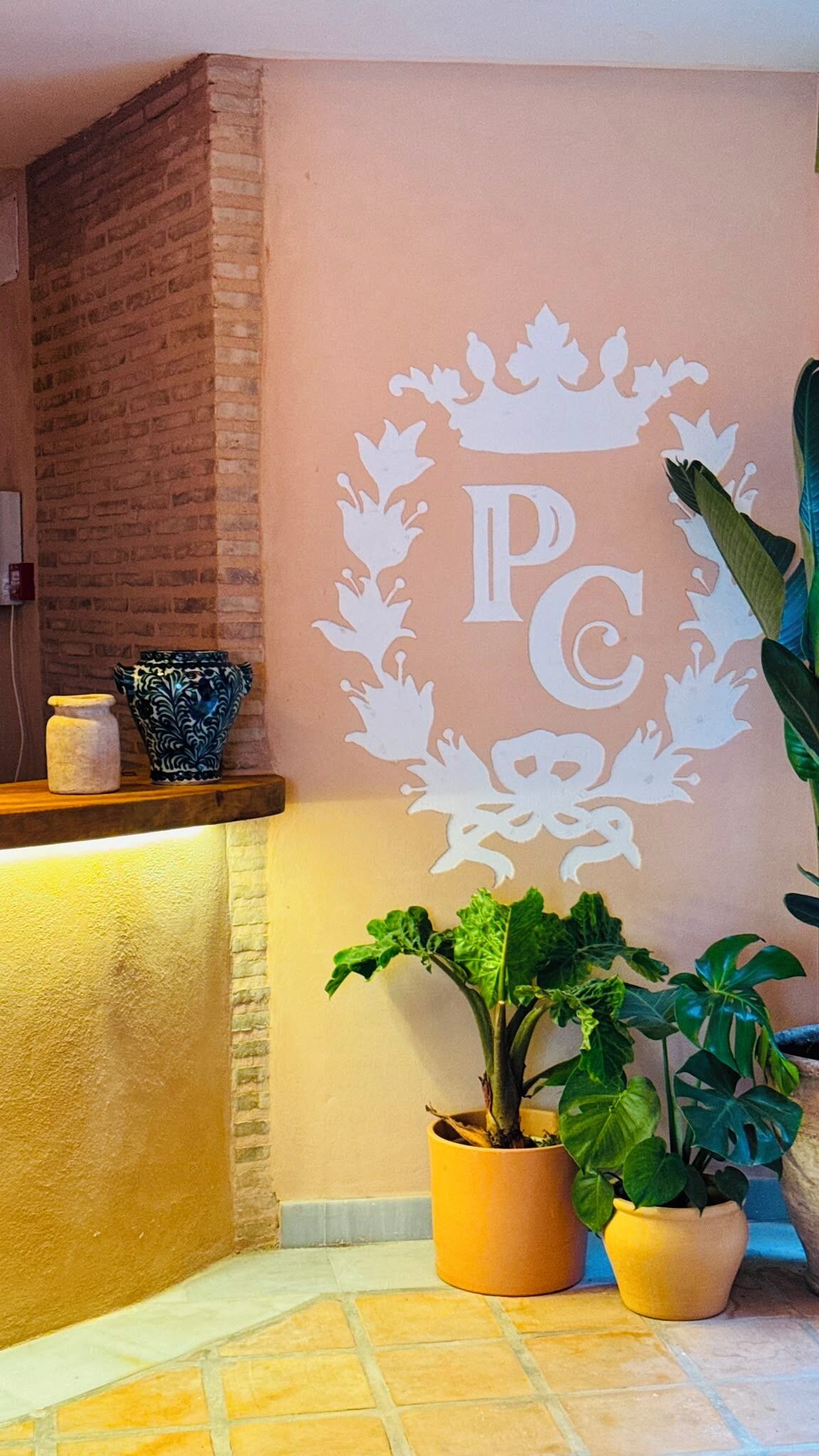 Zona d' recepció amb paret de maó, mostrador i plantes decoratives.