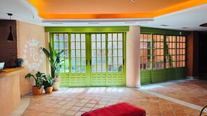 A reception area with a desk, potted plants, and a red bench. - Hotel Boutique Palacete del Corregidor (Almunecar)
