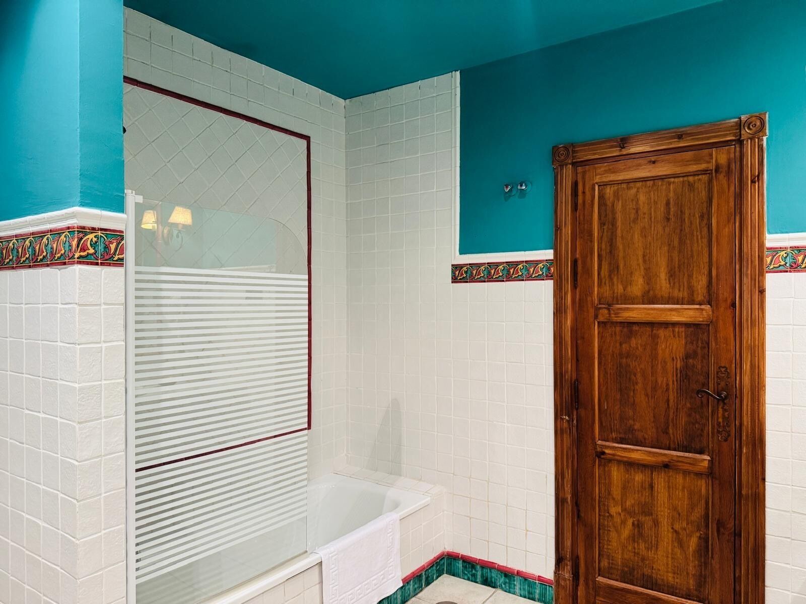 A bathroom with a bathtub, a wooden door, and a shower enclosure.