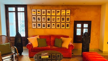 Una sala de estar con un sofá rojo, una mesa de centro y una pared decorada con fotografías enmarcadas.