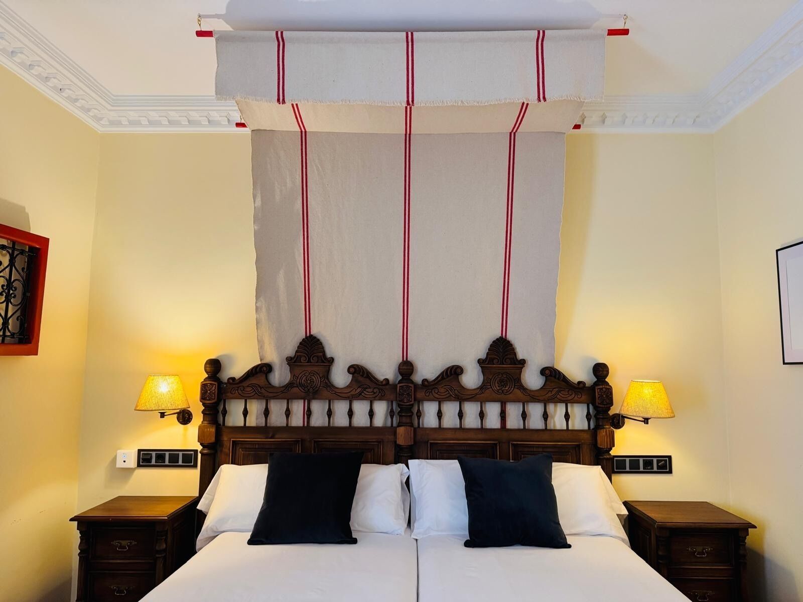 Una cama con cabecera de madera, dos lámparas de noche y un dosel.