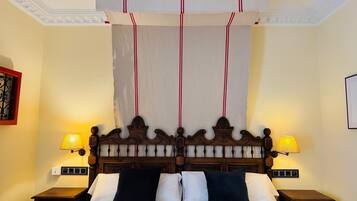 Una cama con cabecera de madera, dos lámparas de noche y un dosel.