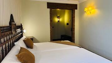 A hotel room with a large bed, a wooden headboard, a nightstand, and a wall-mounted lamp.