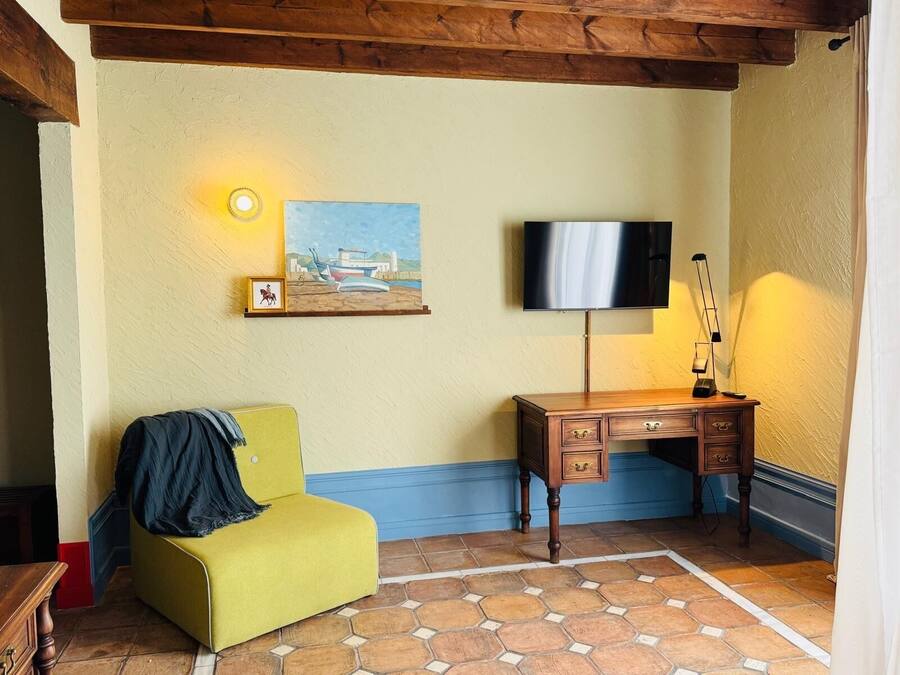 Una habitación con un sofá amarillo, un escritorio de madera, un cuadro y un televisor.