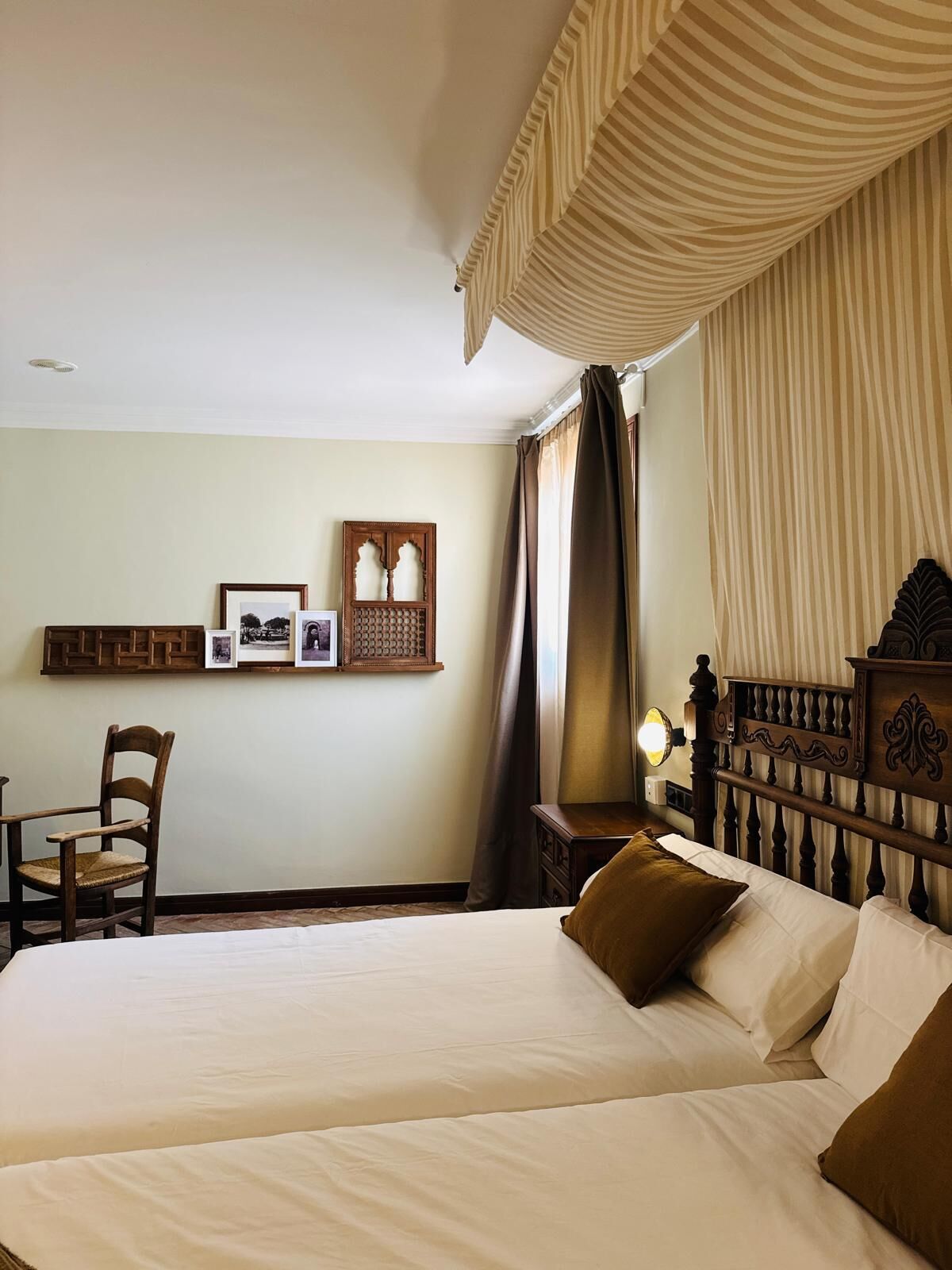 Habitación de hotel con una cama grande, una silla, cabecero de madera y un cuadro colgado en la pared.