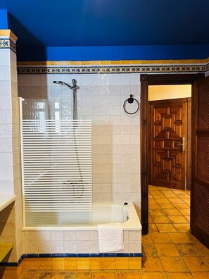 A bathroom with a glass-enclosed shower, a bathtub, and a wooden door. - Hotel Boutique Palacete del Corregidor (Almunecar)