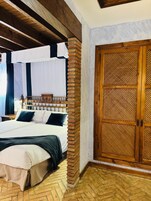 Habitación de hotel con una cama, un armario de madera y un suelo con patrón de espiga.