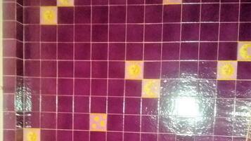 A tiled wall with purple tiles and yellow accents, a yellow floor, and a curved white structure.