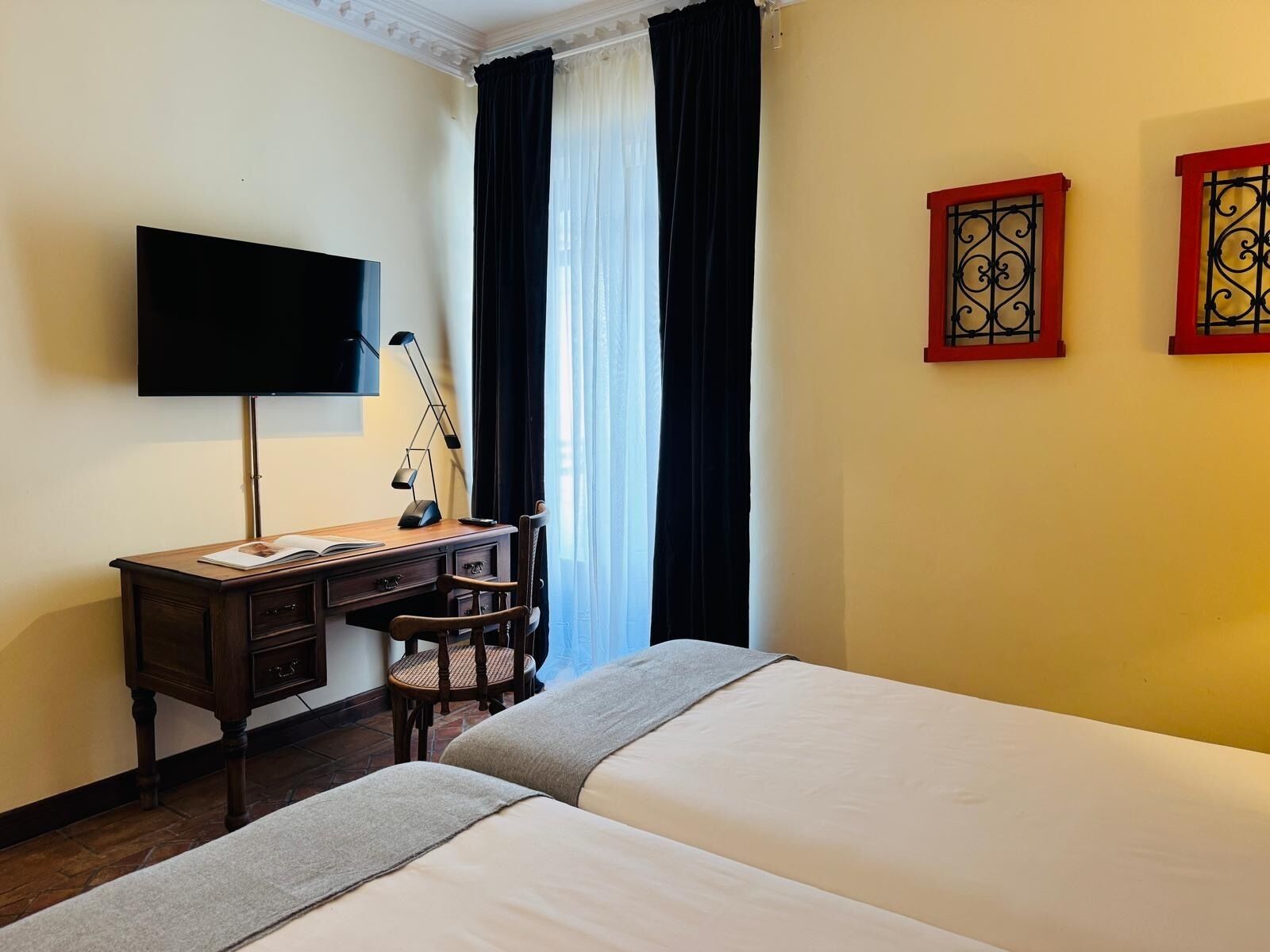Ein Hotelzimmer mit Bett, Schreibtisch, Stuhl, Fernseher und Vorhängen.