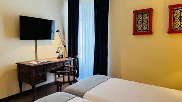 Ein Hotelzimmer mit Bett, Schreibtisch, Stuhl, Fernseher und Vorhängen.