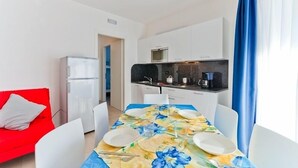 Ein gemütlicher, kleiner Wohnraum mit Essbereich, Küchenzeile und einem roten Sofa.