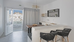 Una cocina moderna con una isla central, taburetes de bar y vistas a un pueblo en la colina.