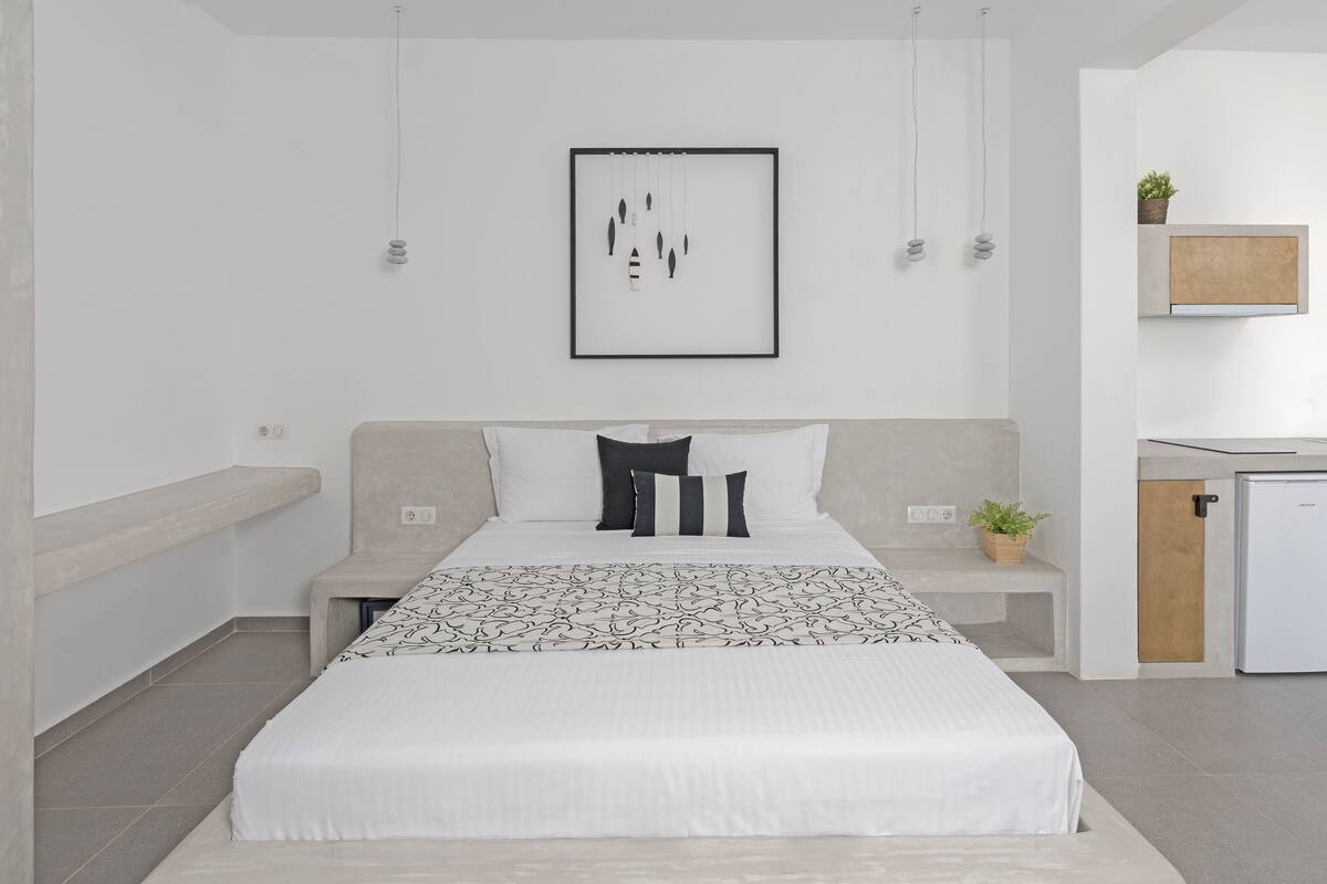 Een moderne slaapkamer met een bed, nachtkastjes, een wandlamp en een lijst met kunstwerk.