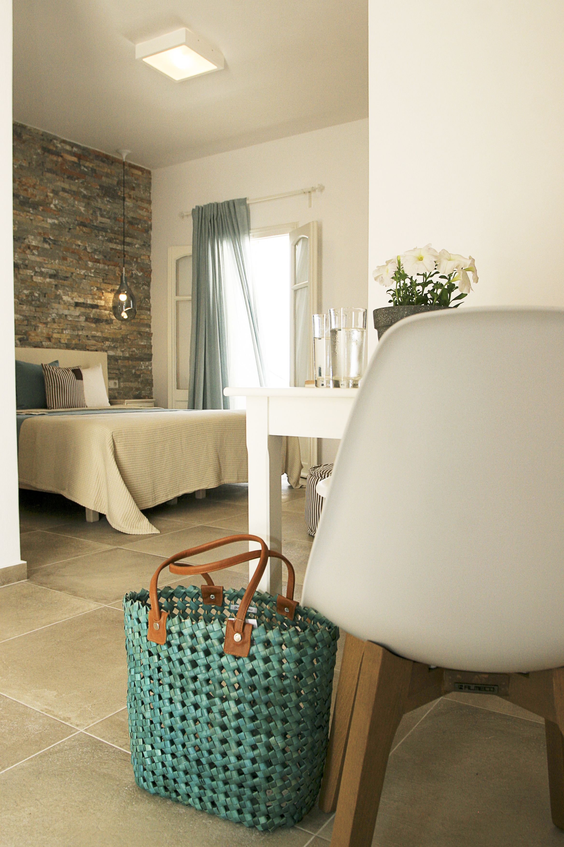 Une chambre à coucher avec un lit, un bureau, une chaise et un sac en tissu tressé.