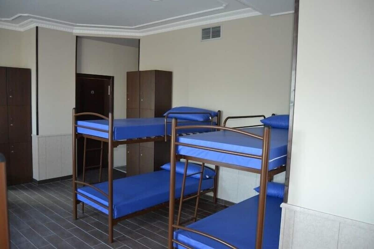 A dormitory room with bunk beds, wooden wardrobes, and a radiator.