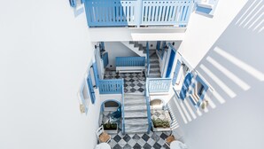 A modern, compact hotel interior with a checkered floor, white and blue decor, and a staircase leading to a balcony. - Fanouris Condo by Meraki Collection Adults Only (18+) accommodation (Santorini)