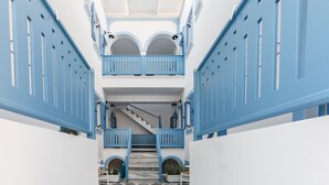 A multi-level building with blue railings and white walls, featuring a central staircase and a checkered floor. - Fanouris Condo by Meraki Collection Adults Only (18+) accommodation (Santorini)