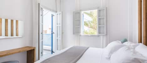 A bedroom with a bed, a wooden bench, and a window with shutters.