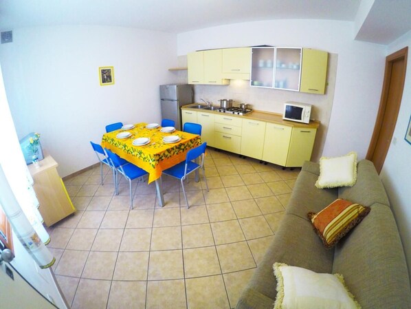 Um espaço compacto com área de refeições, cozinha compacta e sofá.