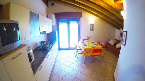 Une cuisine équipée d’une cuisinière, d’un four à micro-ondes et de placards. On y trouve également un coin repas avec une table dressée pour deux personnes et un canapé.