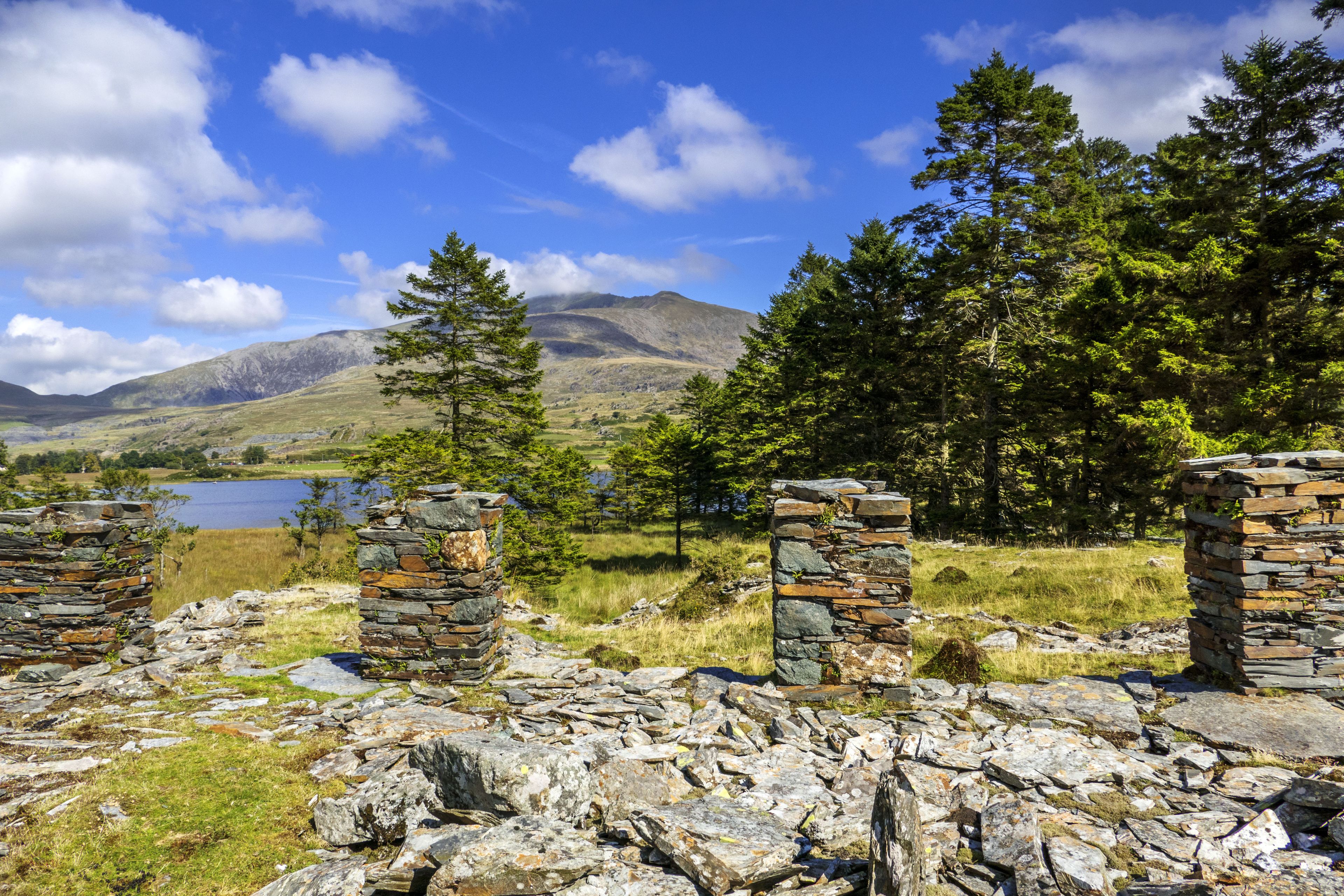 A stone ruin with a view of a lake and mountains in the background.