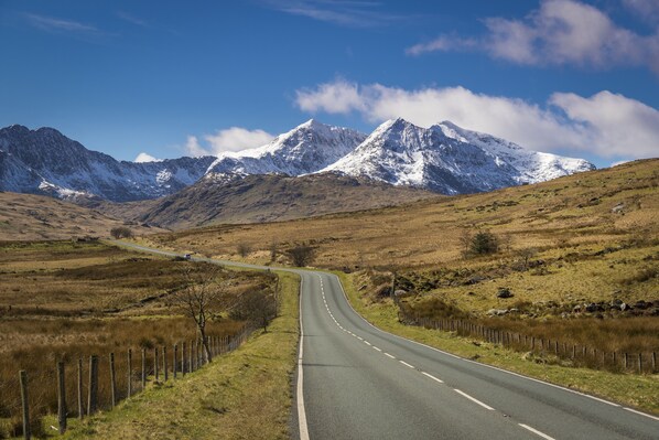 A road leading to a mountainous area with snow-capped peaks. - Plas Tan y Graig (Caernarfon)