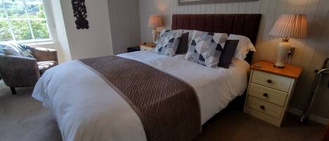 Een keurig opgemaakt bed met een bruine plaid, een hoofdbord en twee bedlampjes.