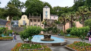 Un jardín con una fuente, bancos y una gran variedad de plantas.